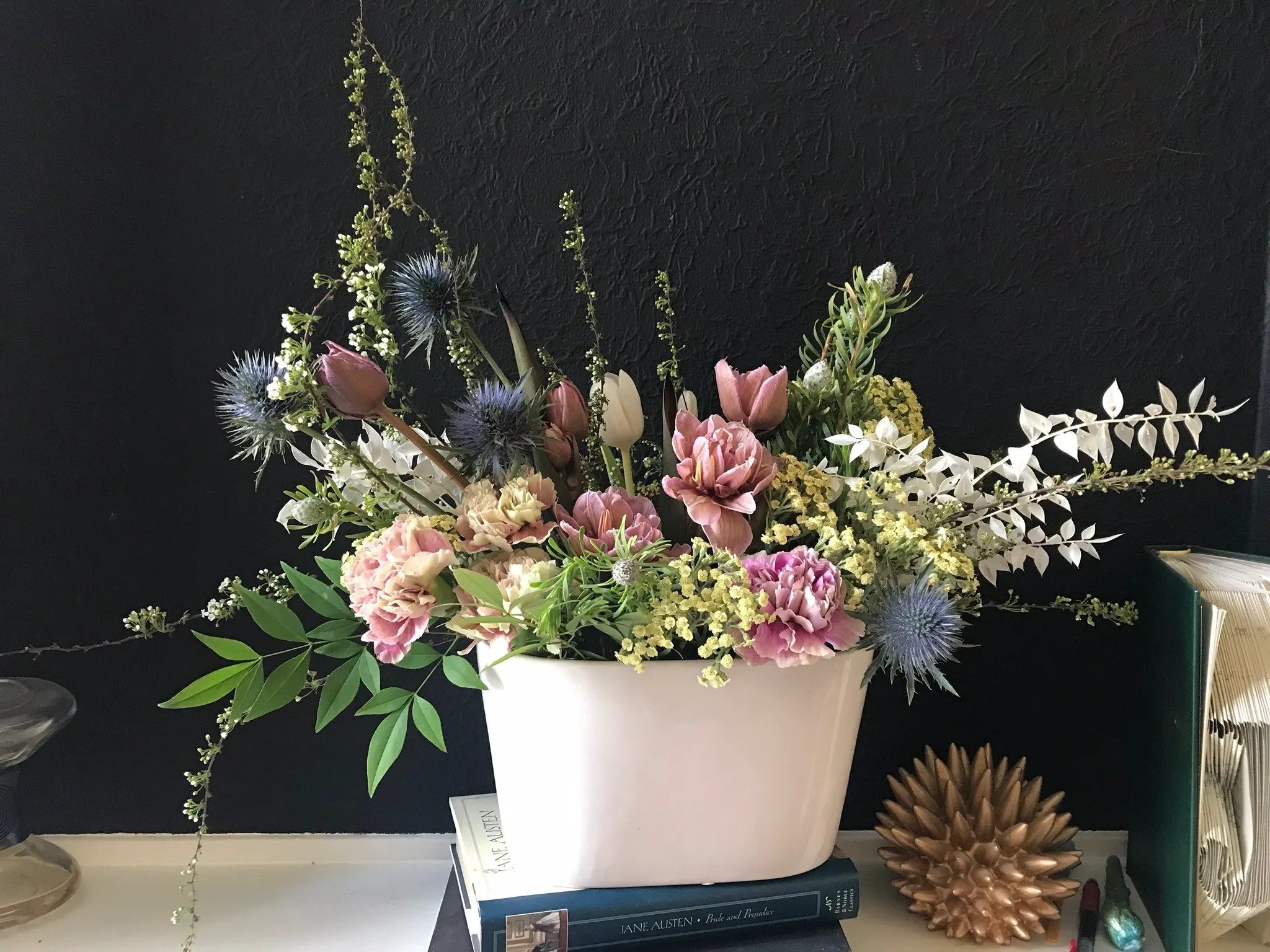 Artisan Meadow luxury floral arrangement featuring mauve tulips, ruffled carnations, structural blue thistles, and arching meadow greenery in a white ceramic trough by Nifty Package Co.