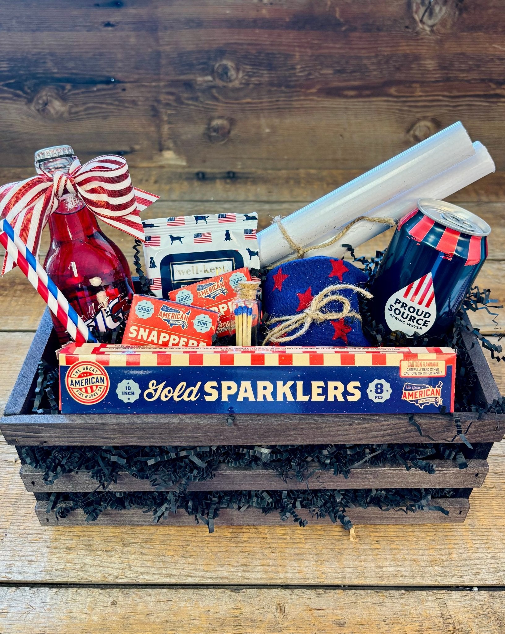 The Snap, Crackle & Pop Patriotic Gift Crate by Nifty Package Co. featuring sparklers, snappers, confetti cannons, and Big Red soda inside a slatted wood box as captured in Patriotic Gift